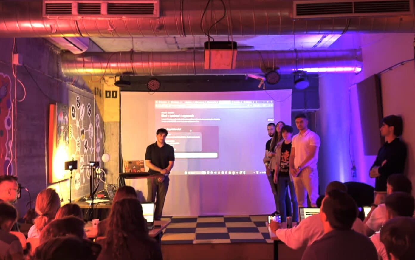 A presenter on the Base42 stage under purple light.